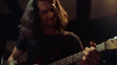 Stüdyoda gitar çalan duygusal bir müzisyen. Besteci içeride müzik üretiyor.