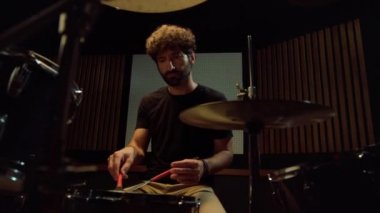 Davulcu konser salonunda prova yapıyor. Müzisyen kayıt stüdyosunda melodi yapıyor.