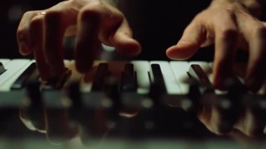 Karanlık salonda müzik yapan müzisyen ellerini piyanonun tuşlarına basıyor..