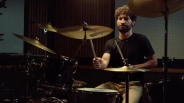 Sanatçı stüdyoda müzik yapıyor. Müzisyen içeride konser programı yapıyor..