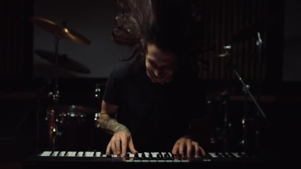 Усміхнений чоловік натискає клавіші в музичній студії. Захоплений хлопець грає на клавіатурі в приміщенні . — стокове відео