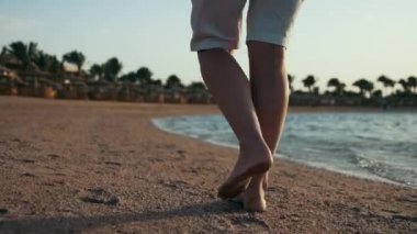 Deniz kenarında yürüyen kadın bacakları. Çıplak ayaklı kız deniz kenarında dinleniyor..