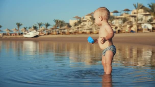 Fröhliches Kind läuft im Sommer abends aus dem Wasser an die Küste. — Stockvideo