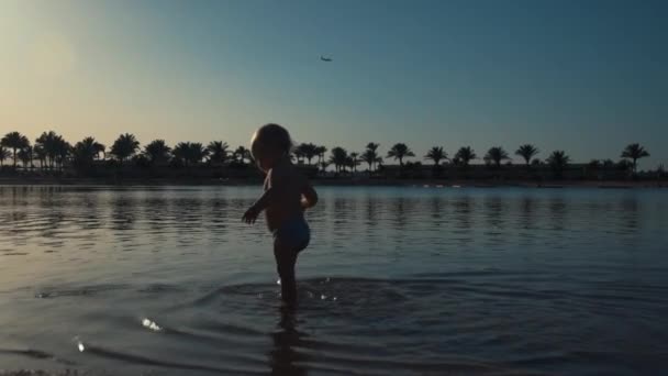Słodki chłopiec spacerujący w morskiej wodzie nad morzem. Szczęśliwy dzieciak korzystających lato na plaży. — Wideo stockowe
