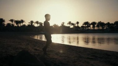 Genç adam deniz kenarında doğanın tadını çıkarıyor. Genç bir çocuk kumsalda yürüyor