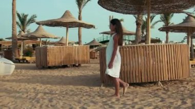 Yaz mevsiminin tadını çıkaran sıska genç bir kadın. Kumsalda yürüyen uzun saçlı kız..