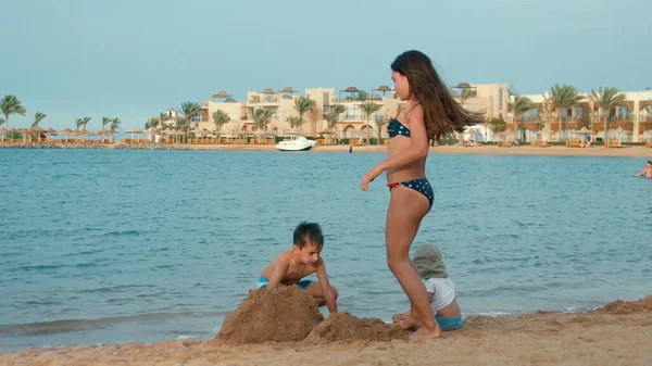 Lindos niños construyendo castillo de arena en la bahía del mar. Niños felices divirtiéndose en playa. — Foto de Stock