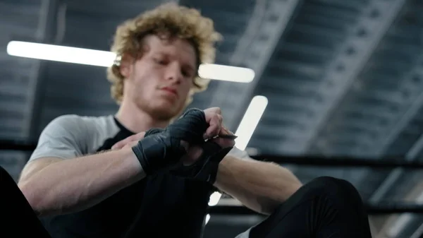 Rozrušený bojovník se připravuje nosit rukavice v tělocvičně. Kickboxer balí ruce — Stock fotografie