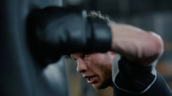 Vzteklý bojovník cvičí ve sportovním klubu. Kickboxer bít boxerský pytel v posilovně — Stock fotografie