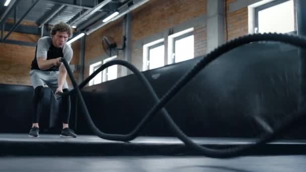 Kickboxer agresivo haciendo ejercicio en el gimnasio. Deportista usando cuerdas de batalla — Vídeos de Stock