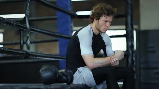 Sad fighter sitting in fitness center. Kickboxer waiting for fight at gym — Stock Video