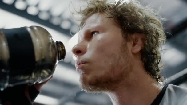 Exhausted fighter quenching thirst in fitness center. Sportsman drinking water — Stock Video