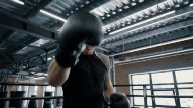 Spor salonunda spor yapan bir boksör. Sporcu ringde saldırganlık gösteriyor.