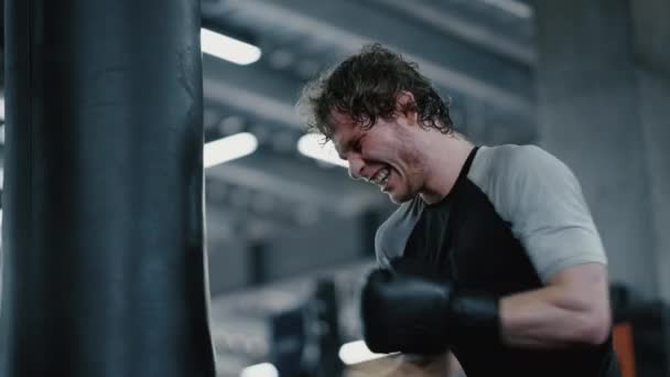 Aggressiv kickboxare visar styrka på gymmet. Sportsman boxning i sport klubb — Stockvideo