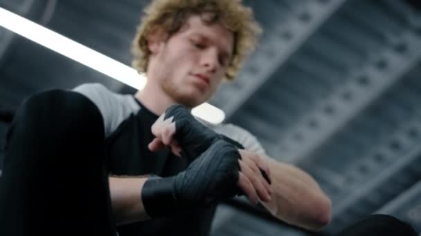 Unavený sportovec připravuje ruce ve sportovním klubu. Fighter pomocí boxerské pásky v tělocvičně — Stock video
