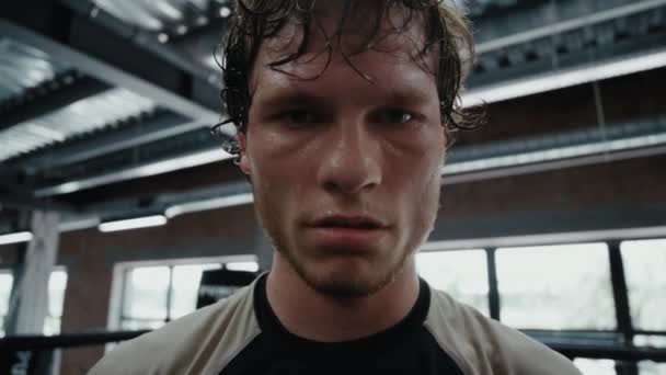 Mladý bojovník zírá na objektiv ve fitness centru. Kickboxer ukazuje agresivitu — Stock video