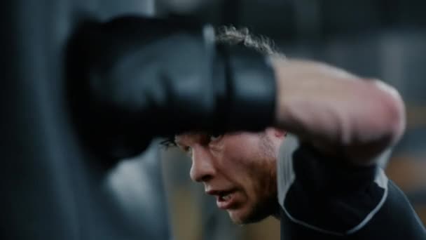 Сердитий боєць робить тренування в спортивному клубі. Кікбоксер вдарив боксерську сумку в спортзалі — стокове відео