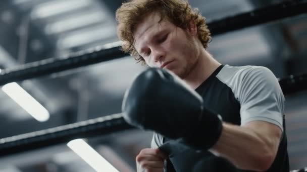 Serious fighter waiting for fight at gym. Kickboxer wearing boxing gloves — Stock Video