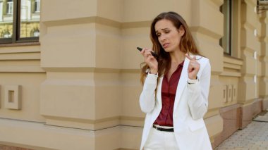 Açık havada cep telefonu kullanan odaklanmış bir iş kadını. Ciddi bir profesyonel.