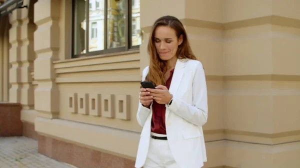 Mulher de negócios brincalhão mensagens no telefone celular ao ar livre. Mulher sorridente — Fotografia de Stock