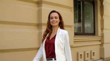 Dışarıda ağır çekimde yürüyen mutlu bir iş kadını. Neşeli iş kadını