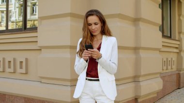 Dışarıda cep telefonu kullanan neşeli bir iş kadını. İnternette ciddi kadın sohbeti.