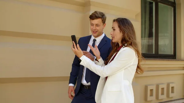 Happy business couple having video call online on mobile phone outdoors