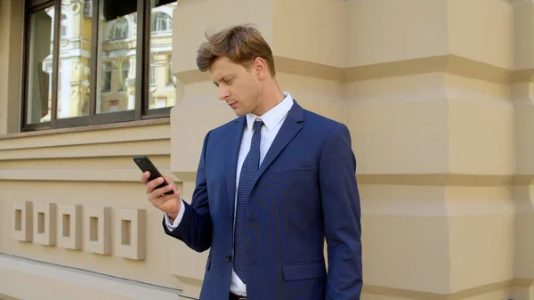 Porträt eines seriösen Geschäftsmannes, der sein Handy im Freien benutzt — Stockfoto