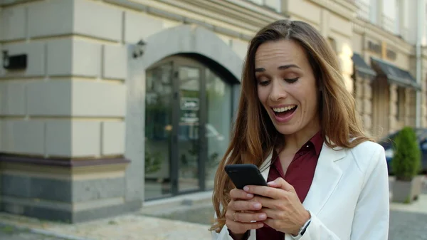 Mulher de negócios surpreso usando telefone celular ao ar livre. Empresária excitada — Fotografia de Stock