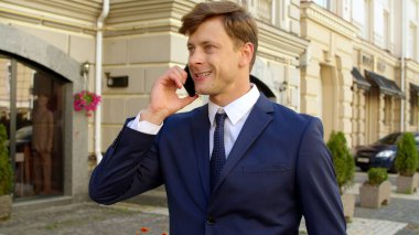 Portre adam kaldırıma bakıyor. Sokakta cep telefonu kullanan bir işadamı.