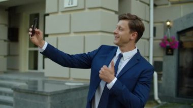 Başarılı bir iş adamı açık havada cep telefonuyla selfie çekiyor..