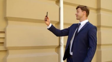 Başarılı iş adamı açık havada cep telefonundan videoyu arıyor.