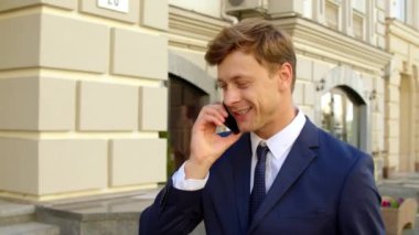 Caddede telefonu kullanan bir portre yöneticisi. Dışarıda telefonla gülümseyen bir adam.