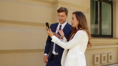 Mutlu iş çifti açık havada cep telefonuyla görüntülü görüşme yapıyor.
