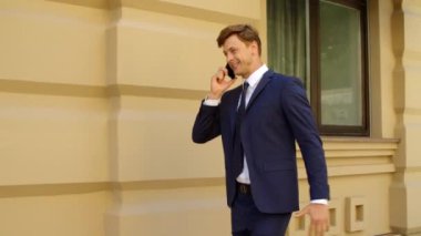 Dışarıda cep telefonundan konuşan heyecanlı bir iş adamı. Mutlu iş adamı