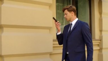 Kafası karışmış bir iş adamı dışarıda cep telefonuyla konuşuyor. Hayal kırıklığına uğramış iş adamı