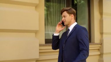 Neşeli iş adamı dışarıda cep telefonundan konuşuyor. Başarılı adam telefonu arıyor.
