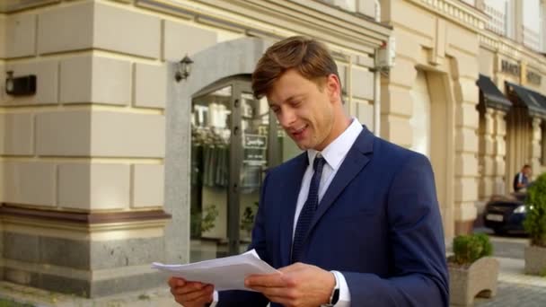 Уверенный бизнесмен читает документы на улице. Возбужденный человек празднует победу — стоковое видео