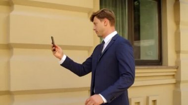 Kapanış konuşması yapan adam dışarıda video görüşmesi yapıyor. Erkek profesyonel sokakta yürüyor.