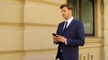 Şehir sokağında cep telefonu kullanan ciddi bir iş adamı. İleti yazan adam