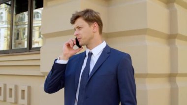 Odaklanmış iş adamı dışarıda cep telefonundan konuşuyor. Kendinden emin iş adamı.