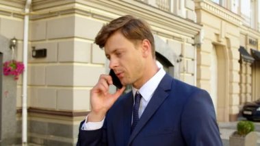 Portreci dışarıda cep telefonuyla konuşuyor. Açık havada akıllı telefonlu bir adam yürüyor.