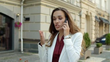 Kızgın iş kadını dışarıda cep telefonuyla tartışıyor. Stresli kadın