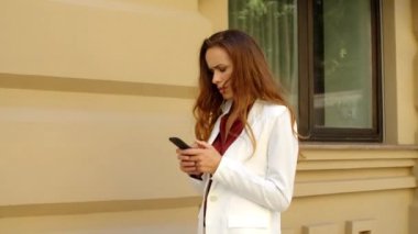 Yakından profesyonel bir kadın dışarı bakıyor. Sokakta telefonu tutan kadın.