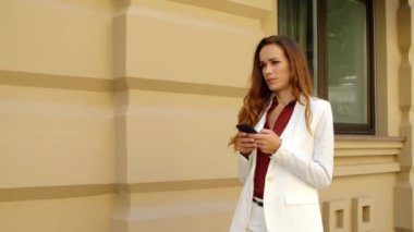Açık havada cep telefonu kullanan odaklanmış bir iş kadını. Düşünceli kadın yürüyor.