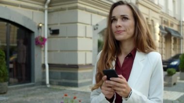 Mutlu iş kadını dışarıda akıllı telefondan mesaj yolluyor.
