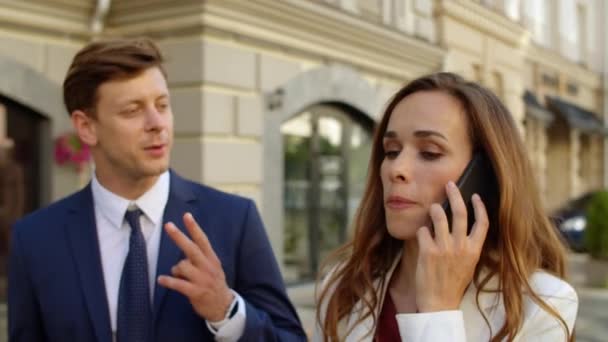 Успешная деловая пара ведет переговоры по мобильному телефону на открытом воздухе — стоковое видео