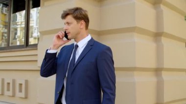Stresli iş adamı dışarıda cep telefonundan konuşuyor. Kızgın iş adamı
