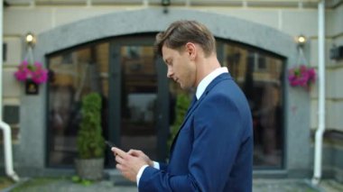 İş adamı dışarıda akıllı telefondan mesaj atıyor. Sokakta yürüyen düşünceli bir adam.