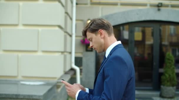 Homme d'affaires sérieux utilisant le téléphone mobile en ligne à l'extérieur — Video